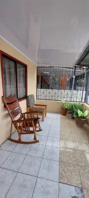 a patio with two rocking chairs and a table at HOSTEL CASA MARINA in Puerto Limón