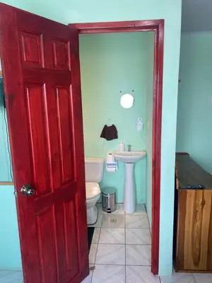 a bathroom with a red door and a toilet at HOSTEL CASA MARINA in Puerto Limón