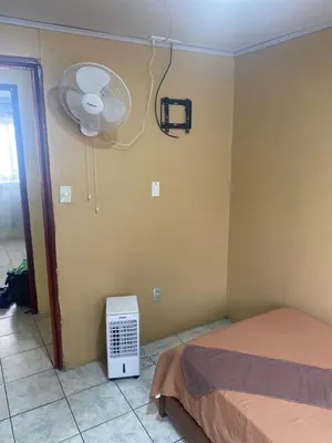 a room with a bed and a fan in it at HOSTEL CASA MARINA in Puerto Limón