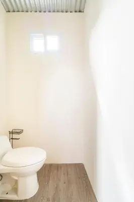 a white bathroom with a toilet and a window at Glamping en Playa Potrero in Potrero