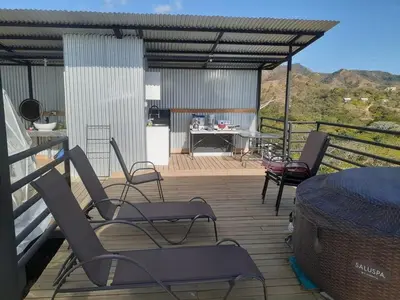 a deck with chairs and a table and a grill at Glamping en Playa Potrero in Potrero
