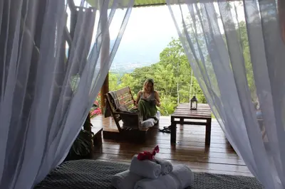 a woman sitting in a chair on a porch at Hacienda Monteclaro in Turrialba