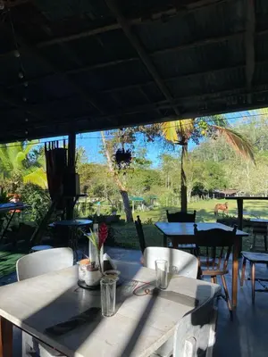 a restaurant with a table and chairs and a view of a park at Hacienda Monteclaro in Turrialba