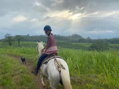 a woman riding a white horse in a field at Hacienda Monteclaro in Turrialba