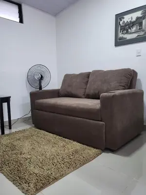 a brown couch in a living room with a rug at EcoStudio in San José
