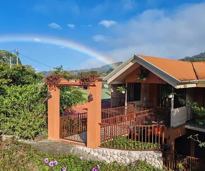 a rainbow over a house with a balcony at Mi Casa Su Casa Monteverde in Monteverde Costa Rica