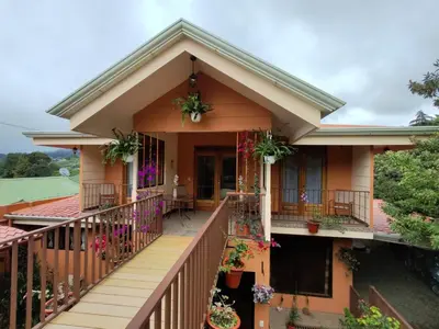 a house with a balcony with flowers on it at Mi Casa Su Casa Monteverde in Monteverde Costa Rica