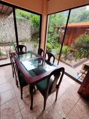 a dining room table with chairs and a large window at Mi Casa Su Casa Monteverde in Monteverde Costa Rica