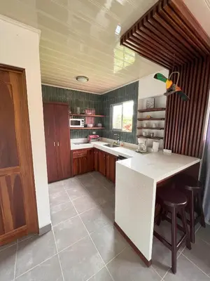 a kitchen with a white counter top and wooden cabinets at La Casa Pina Pacifica near La Fortuna in San Ramón