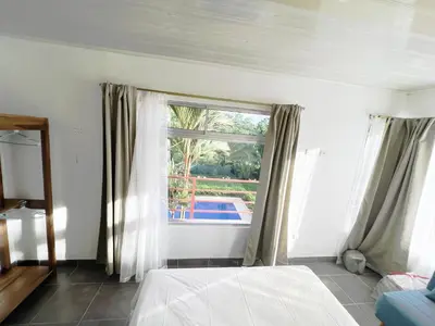a bedroom with a bed and a window with a pool at La Casa Pina Pacifica near La Fortuna in San Ramón