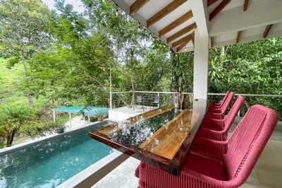 a glass table and chairs on a porch with a swimming pool at Tropical Casa Ventanas with private pool in MA in Quepos
