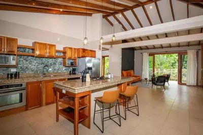 a kitchen with wooden cabinets and a large island at Tropical Casa Ventanas with private pool in MA in Quepos