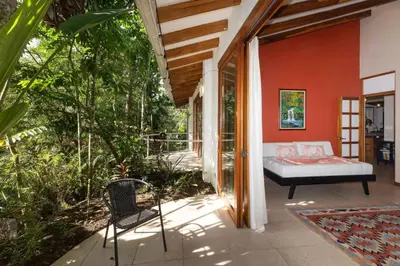 a bedroom with a bed and a chair on a patio at Tropical Casa Ventanas with private pool in MA in Quepos