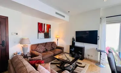 a living room with a couch and a flat screen tv at Acqua Residences 5 Star in Jacó