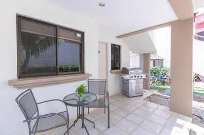 a patio with a table and chairs and a grill at Pacific Sunset Ground Unit Condo across the beach in Coco