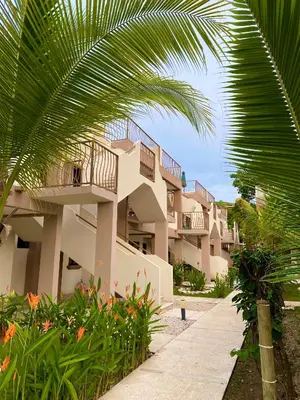 a building with a palm tree in front of it at Pacific Sunset Ground Unit Condo across the beach in Coco