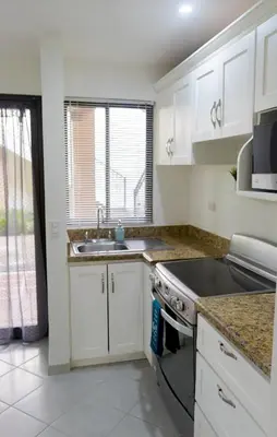 a kitchen with white cabinets and a sink and a stove at The Beach House Ground Floor Condo in Coco
