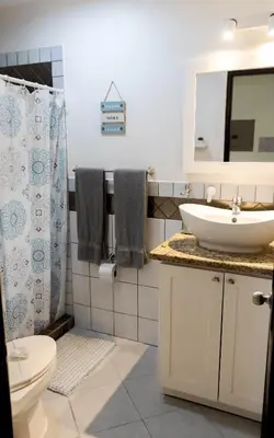 a bathroom with a sink and a toilet and a mirror at The Beach House Ground Floor Condo in Coco