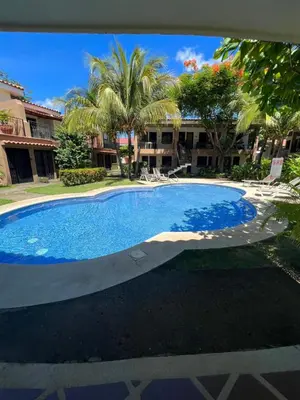 a large swimming pool in a yard with palm trees at The Beach House Ground Floor Condo in Coco