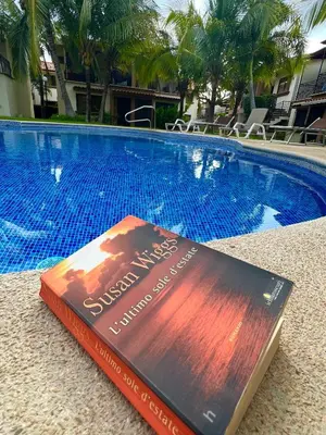 a book laying on the ground next to a swimming pool at The Beach House Ground Floor Condo in Coco
