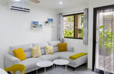 a white living room with a white couch and yellow pillows at The Beach House Ground Floor Condo in Coco