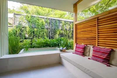 a window seat in a room with a large window with a view of a garden at Botanika Suites in Santa Teresa Beach