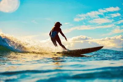 a woman riding a wave on a surfboard in the ocean at Colores del Viento - by Pura Villas in Uvita