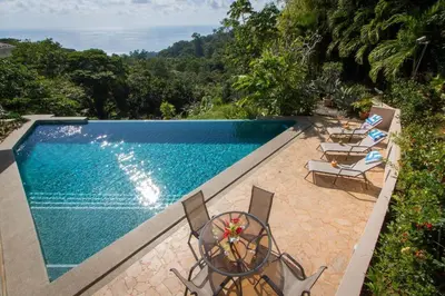 a swimming pool with chairs and a table next to it at Colores del Viento - by Pura Villas in Uvita