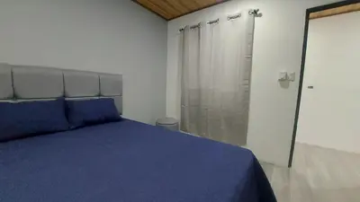 a bedroom with a blue bed and a shower at Casas Doña Juanita in Jacó