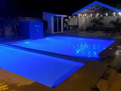 a swimming pool lit up in blue at night at Casas Doña Juanita in Jacó