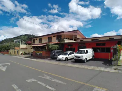 two cars parked in a parking lot in front of a building at Hotel Valle Verde in San Joaquín