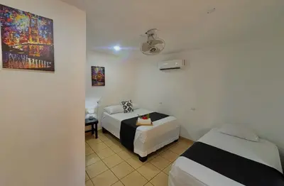 a room with two beds and a table in it at Carey Lodging in Tortuguero