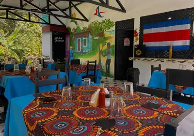 a dining room with blue tables and a painting on the wall at Carey Lodging in Tortuguero