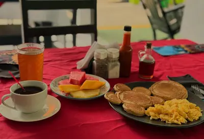 a table with a plate of breakfast food and a cup of coffee at Carey Lodging in Tortuguero