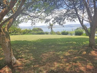 a green field with trees and water in the background at TOP RATED - Stunning Lake Arenal 2 Bed Country House in Tronadora