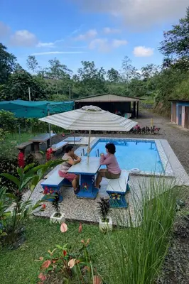 two women sitting at a table next to a pool at Jungle Cabin w Pool & Nature Trails in Venecia