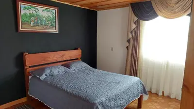 a bedroom with a bed with a blue blanket and a window at El Descanso Restaurante y Hotel in Fraijanes