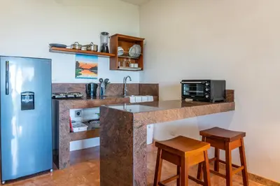 a kitchen with a counter with two stools and a refrigerator at Mot Mot Vacation in Sámara