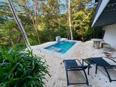 a swimming pool with two chairs and a table at Pinilla Highlands Incredible mountain views in Tamarindo