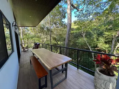 a porch with a wooden table and bench on a balcony at Pinilla Highlands Incredible mountain views in Tamarindo