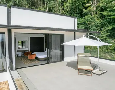a white house with a bed and an umbrella at Villa Setai - Full Ocean view in Santa Teresa Beach