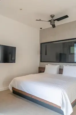 a bedroom with a white bed with a ceiling fan at Villa Setai - Full Ocean view in Santa Teresa Beach