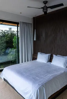 a bedroom with a bed with white sheets and a window at Villa Setai - Full Ocean view in Santa Teresa Beach