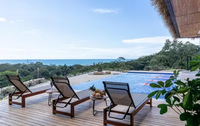 a deck with four chairs and a swimming pool at Villa Setai - Full Ocean view in Santa Teresa Beach