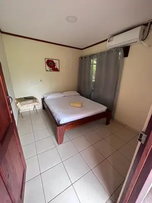 a small bedroom with a bed and a tiled floor at RIVER SIDE LODGE in Horquetas