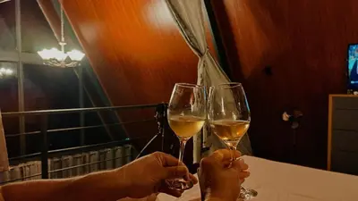 two people holding glasses of white wine on a table at Yarumo Lodge, Río Celeste Black Chalets in Bijagua