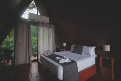 a bedroom with a bed and a large window at Yarumo Lodge, Río Celeste Black Chalets in Bijagua