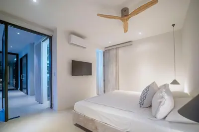 a white bedroom with a bed and a tv at KUNUK- Walk to Hermosa beach in Santa Teresa Beach