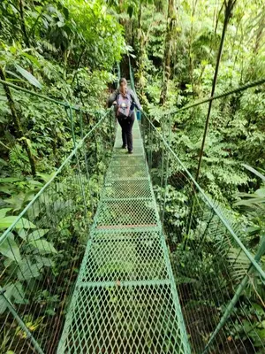 a woman walking across a suspension bridge in the forest at Hotel Finca 360 in Marsella