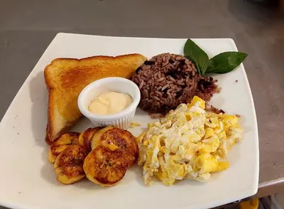 a plate of breakfast food with toast and scrambled eggs at Hotel M&M Beach House in Coco